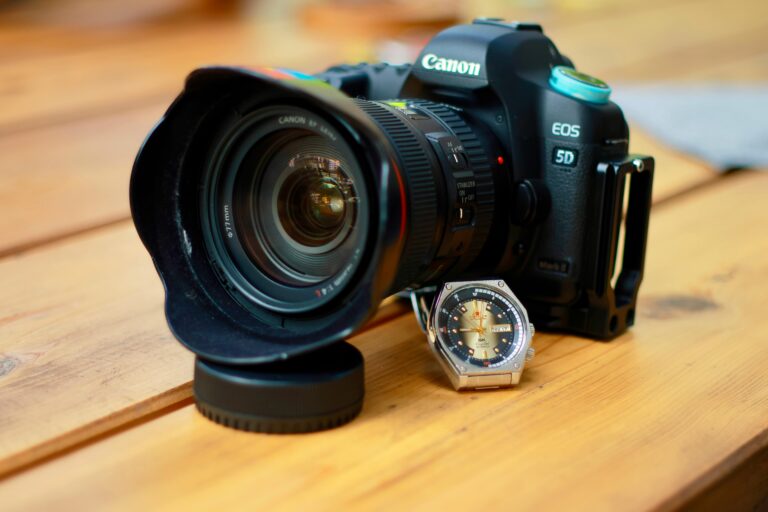Detailed image of Canon camera and wristwatch on a wooden surface.