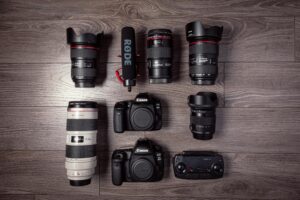 Flat lay of professional photography equipment including cameras, lenses, and microphone.
