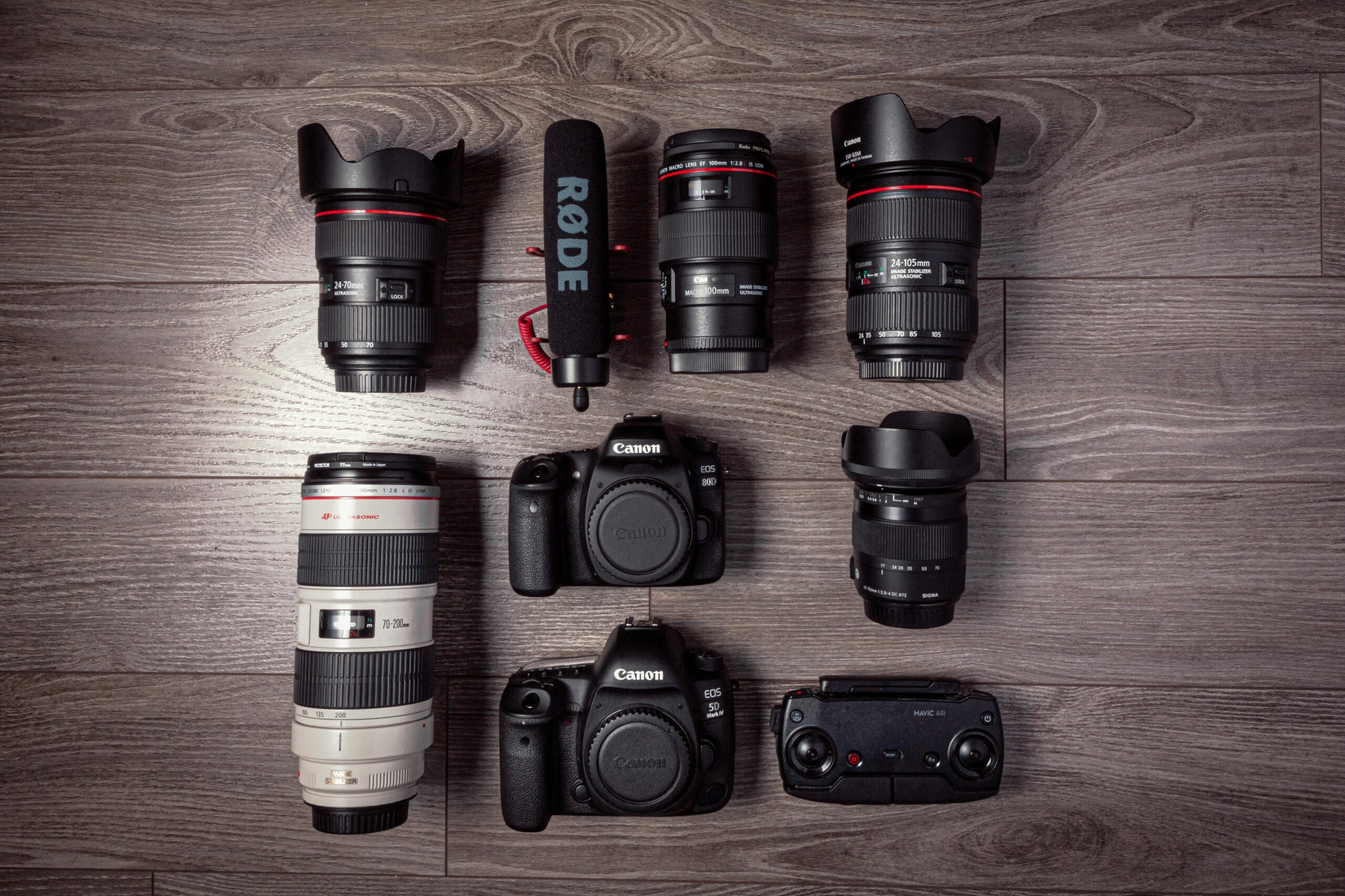 Flat lay of professional photography equipment including cameras, lenses, and microphone.