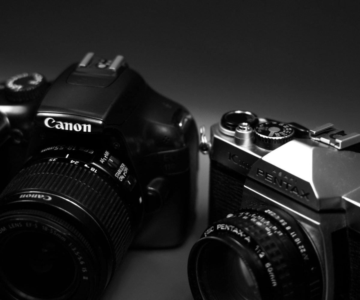 Close-up of Canon and Pentax cameras in black and white, showcasing vintage and modern design.